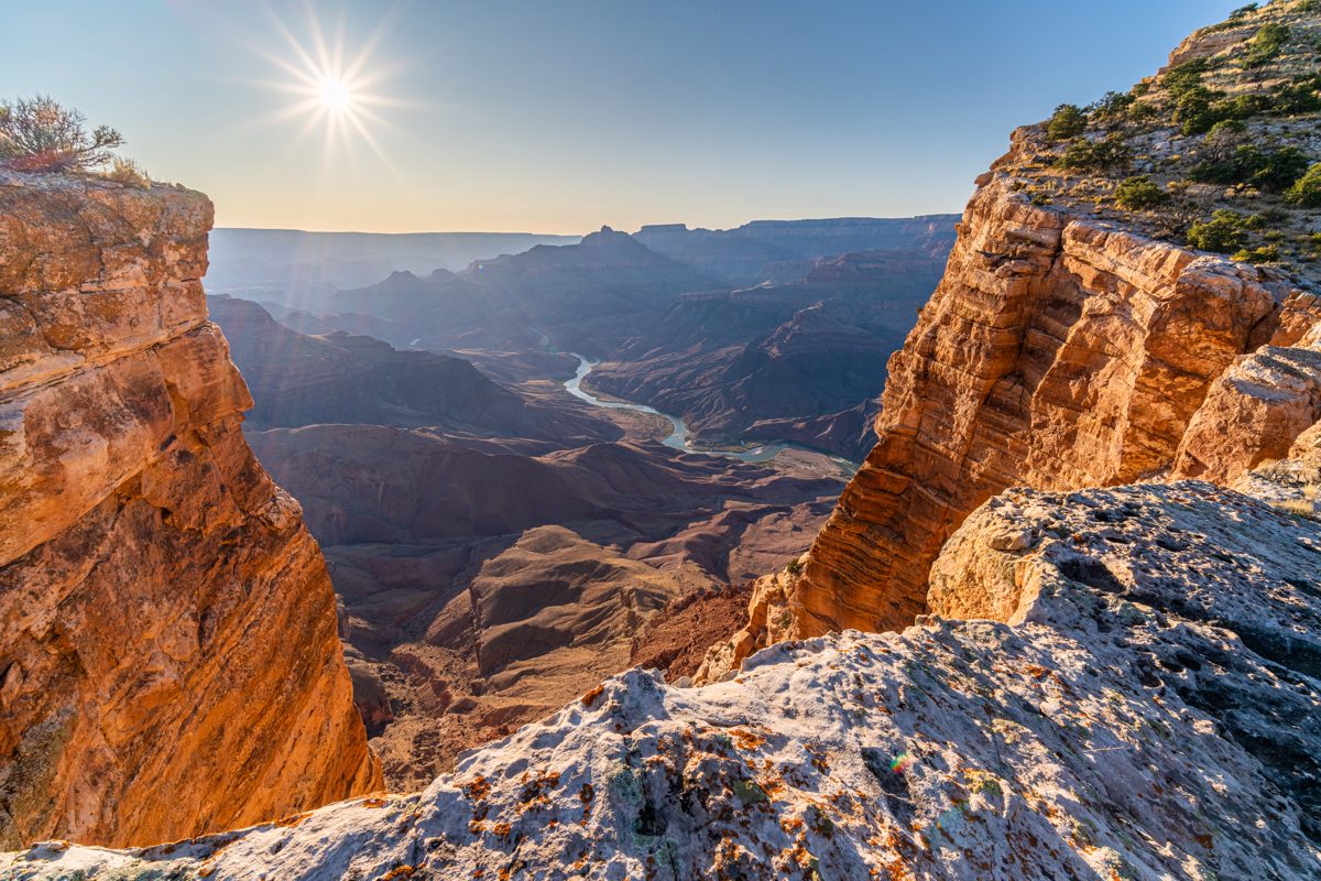 Standing on tall cliffs lit by late day light - looking down on the Colorado River in the Grand Canyon.