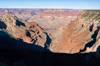 A deep canyon emerges from deep shadow and curves down towards an unseen meeting with the Colorado River.