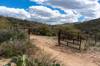 An open corral gate leads out onto Forest Service land on an old dirt road.