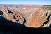 A deep canyon emerges from deep shadow and curves down towards an unseen meeting with the Colorado River.