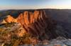 Cliffs edge in the foreground with sunset lit cliffs stretching towards the nearly too small to see Desert View Watch Tower.