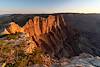 Cliffs edge in the foreground with sunset lit cliffs stretching towards the nearly too small to see Desert View Watch Tower.