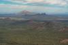 A landscape of Saguaro flats and small hills stretches towards a light colored and a dark colored peak in the distance - Newman and Pichacho.