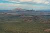 A landscape of Saguaro flats and small hills stretches towards a light colored and a dark colored peak in the distance - Newman and Pichacho.