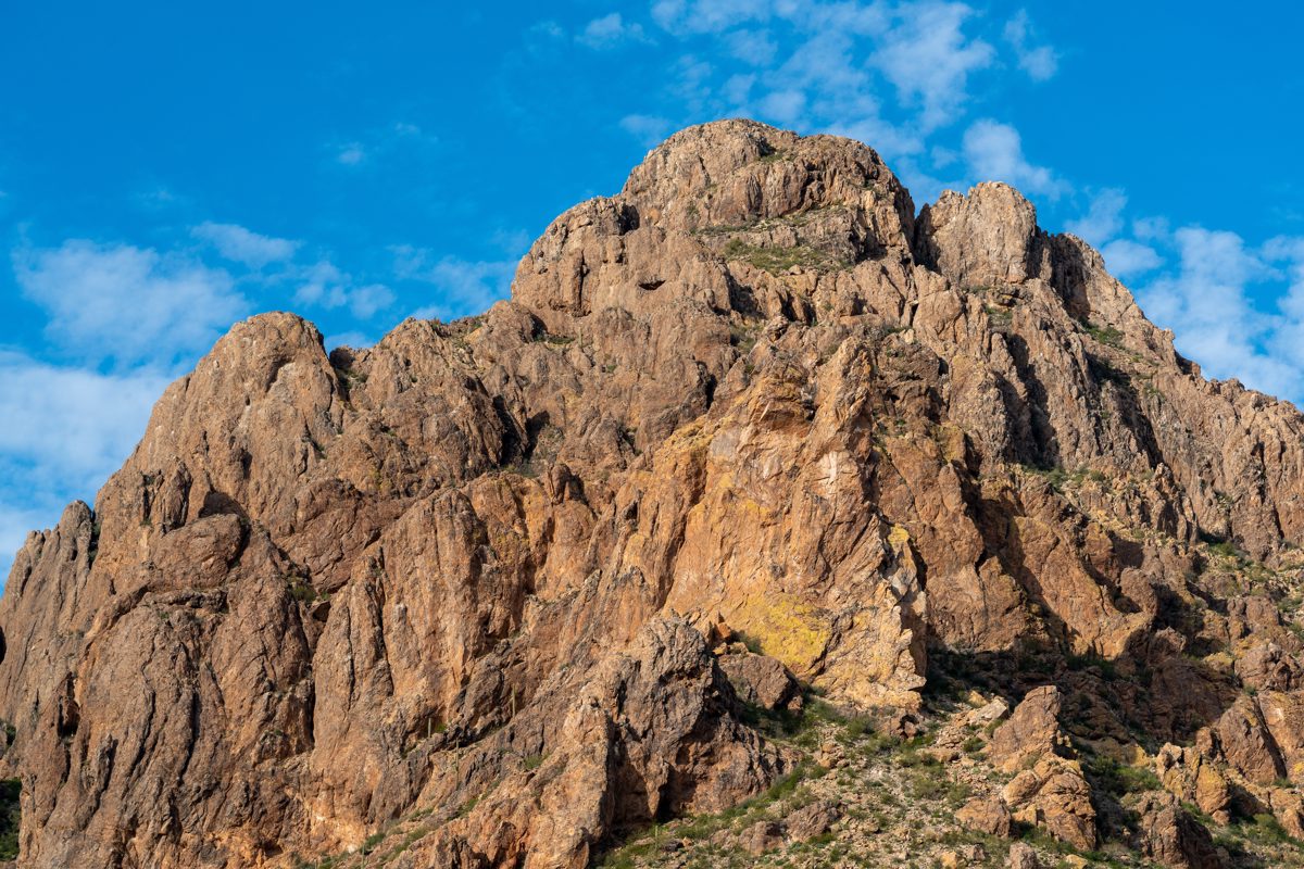 Jagged rough rocky broken cliffs surround a slightly rounded summit.