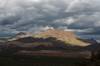 A window of sunlight highlights Silver Bell Peak and nearby ridgeline with storm clouds above and the Silver Bell Mine covered in shadows below.