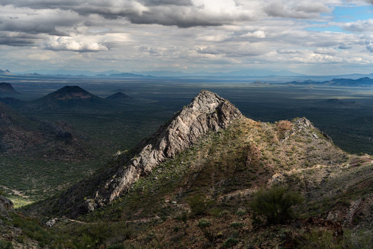 A sunlit rocky ridgeline is surrounded by shadows in the Waterman Mountains.